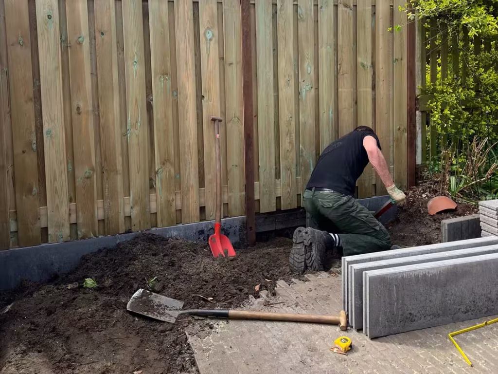 Hovenier plaatst afsluitband onder nieuwe schutting in Vlaardingen – Vonk Tuinen.