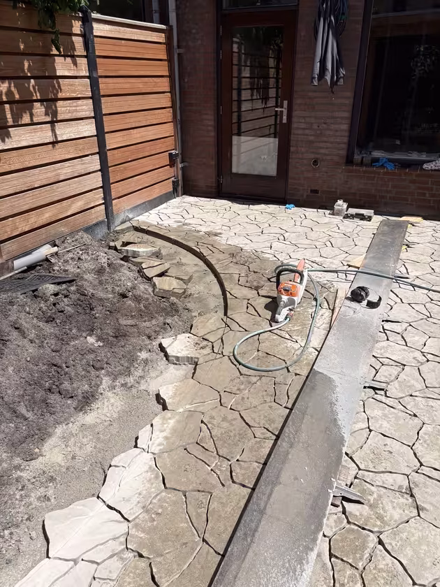 Eerste deel van de uitgeslepen borderlijn met de Cortenstaal rand er naast het terras.